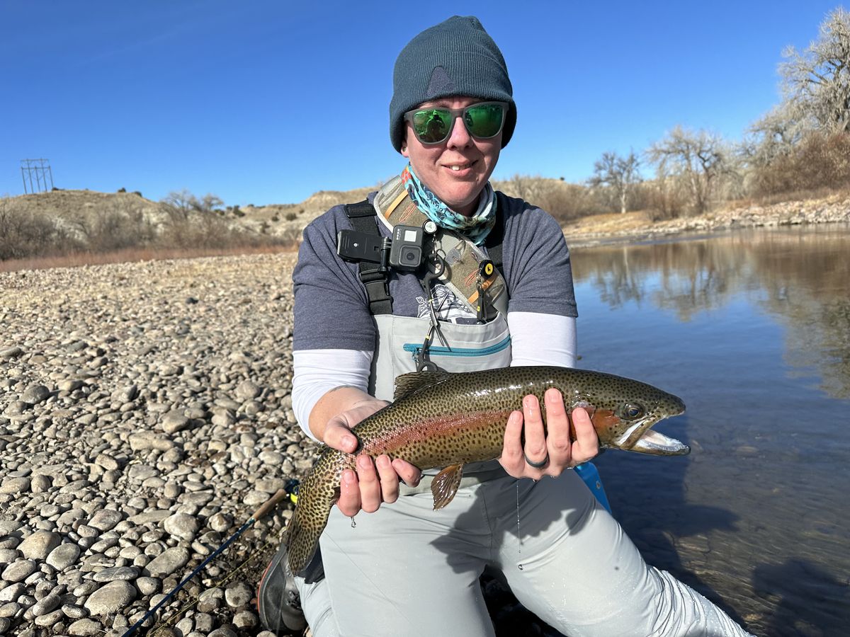 Niki Mosier holding a rainbow trout while fly fishing on a Colorado river